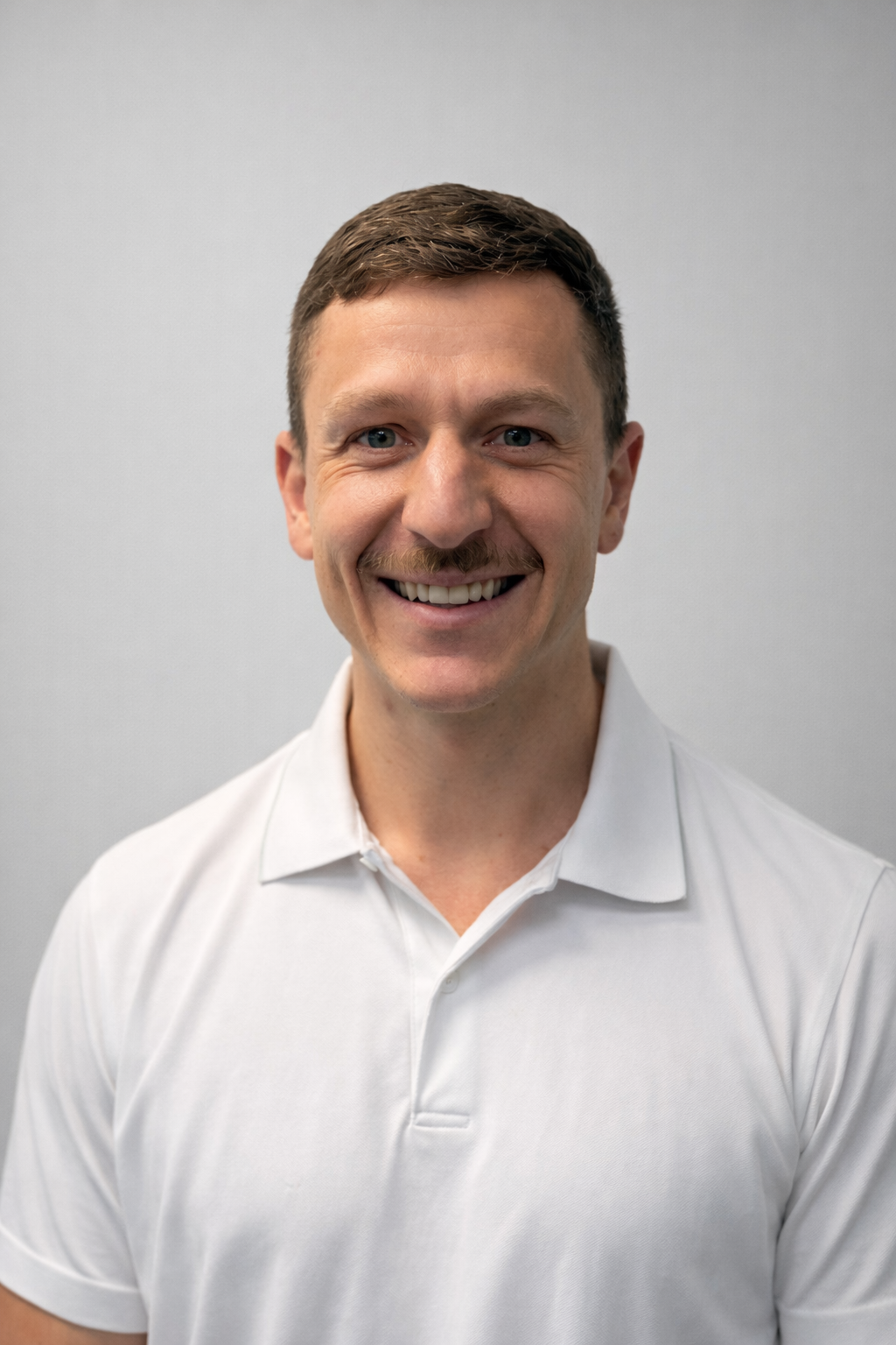 A man in a black shirt is standing in front of a barbell in a gym.