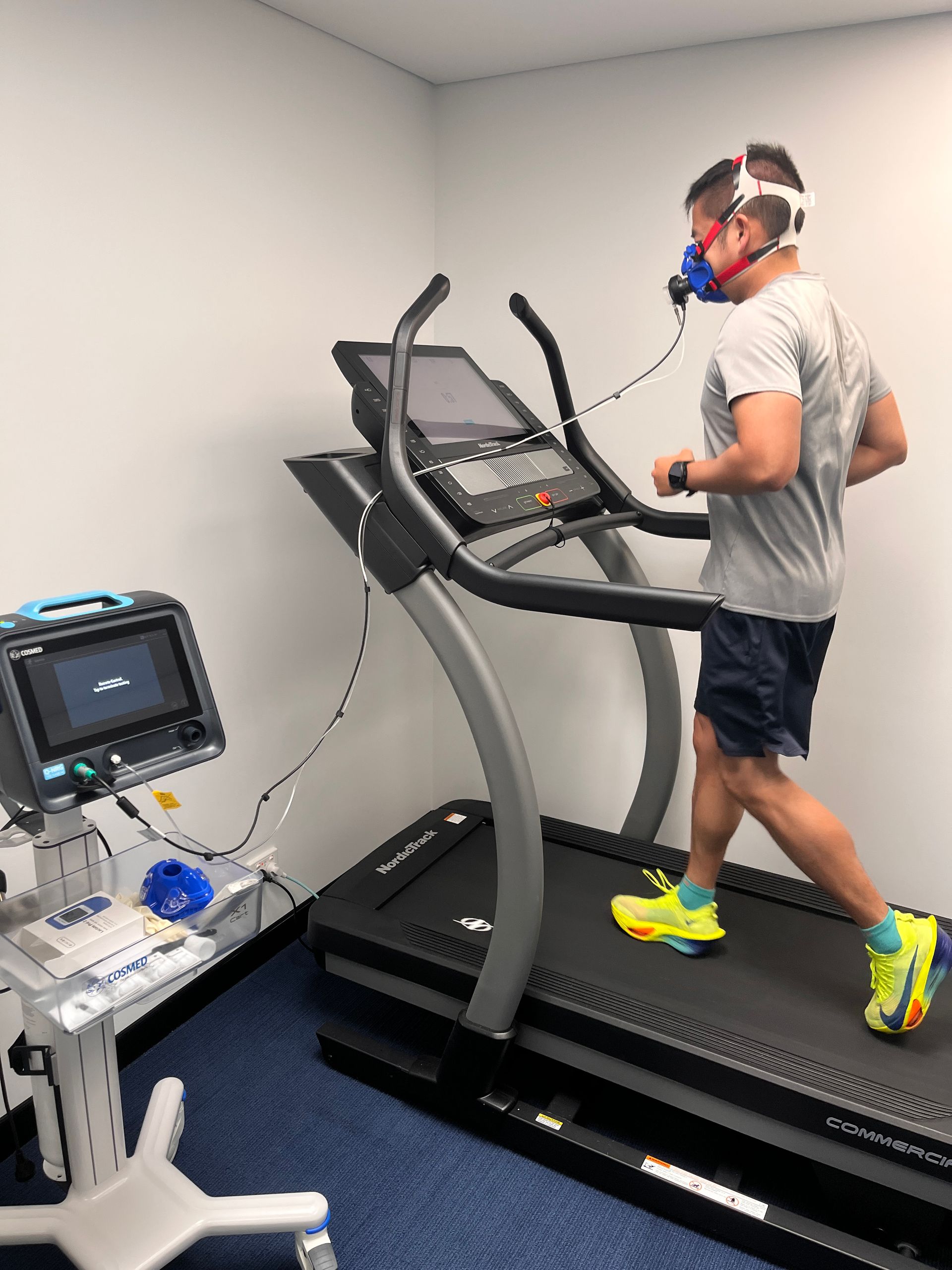A man wearing a mask is running on a treadmill.
