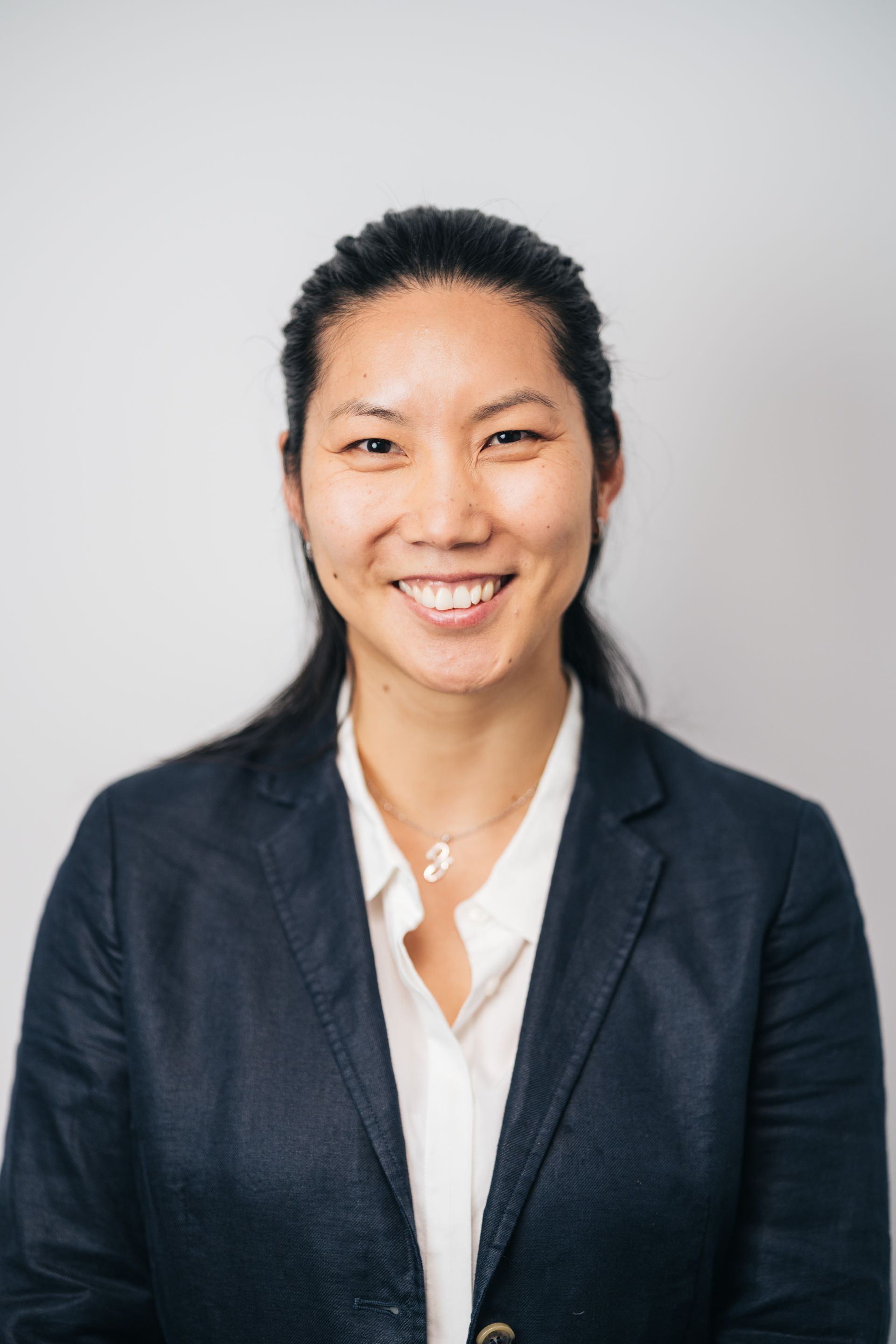 A woman in a suit and white shirt is smiling for the camera.