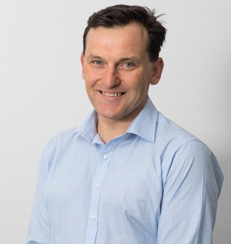 A man in a blue shirt is smiling for the camera.