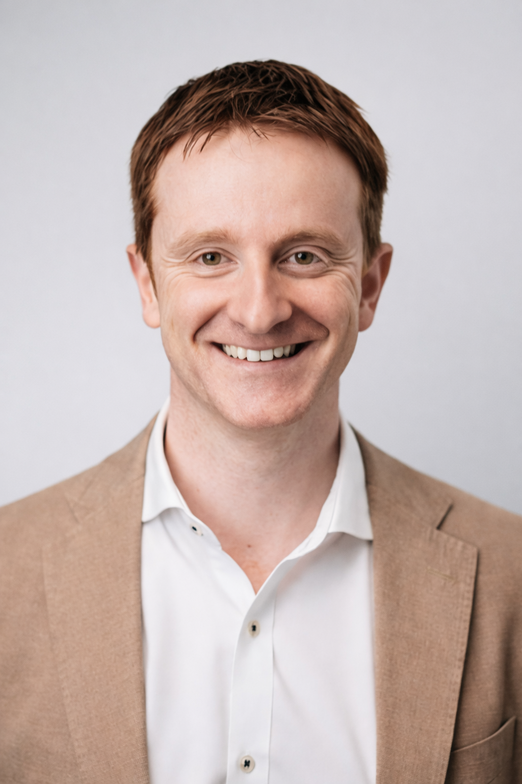 A man in a suit and white shirt is smiling for the camera.