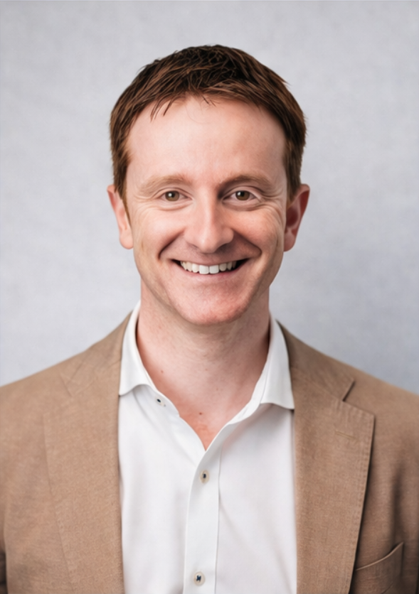 A man in a suit and white shirt is smiling for the camera.