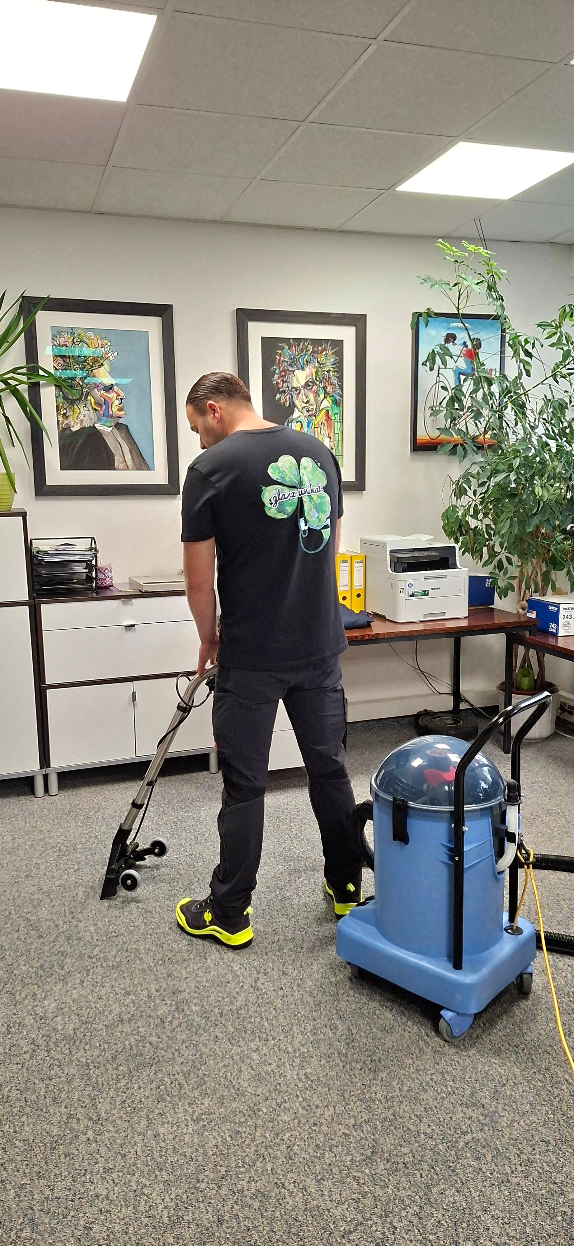 Eine Person benutzt in einem Büro einen Teppichreiniger mit blauem Gerät.