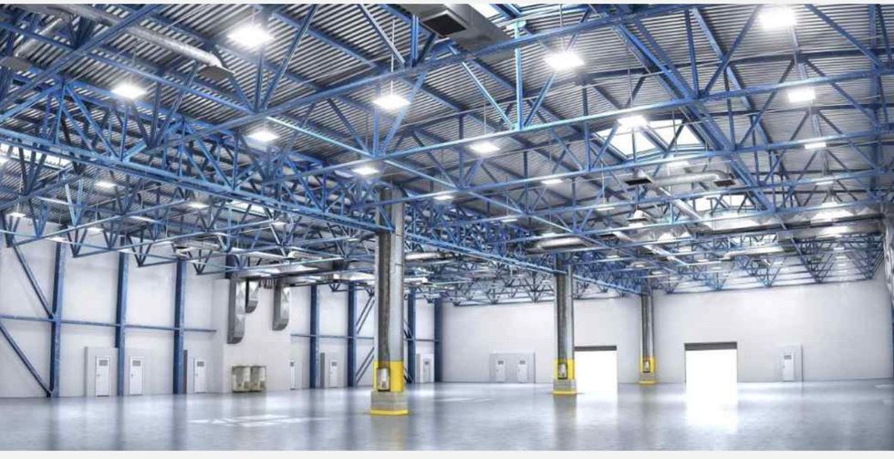 A large empty warehouse with lots of lights on the ceiling.