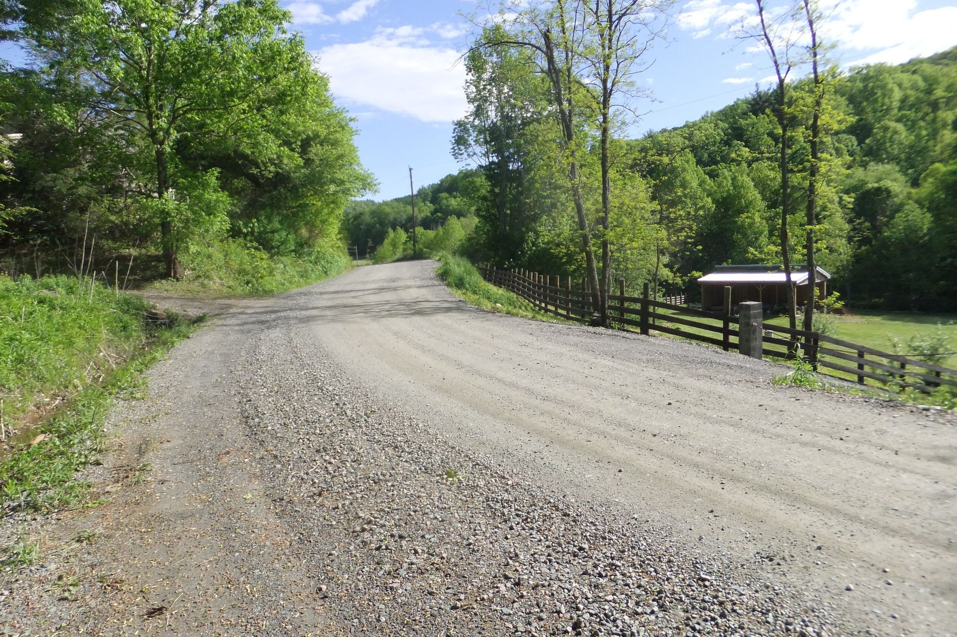 A gravel road with a fence on the side of it