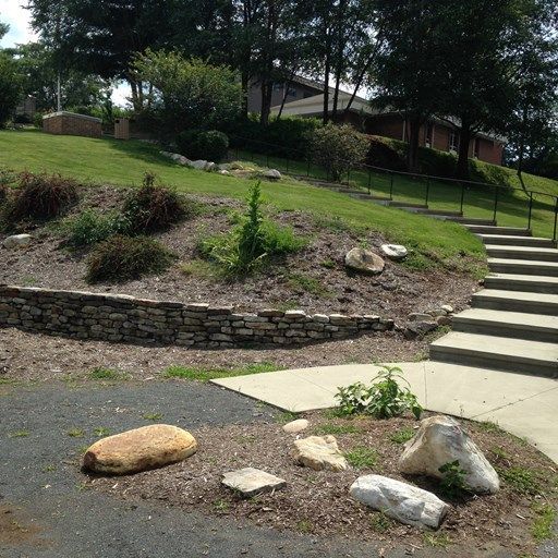 A stone wall and stairs leading up to a grassy hillside