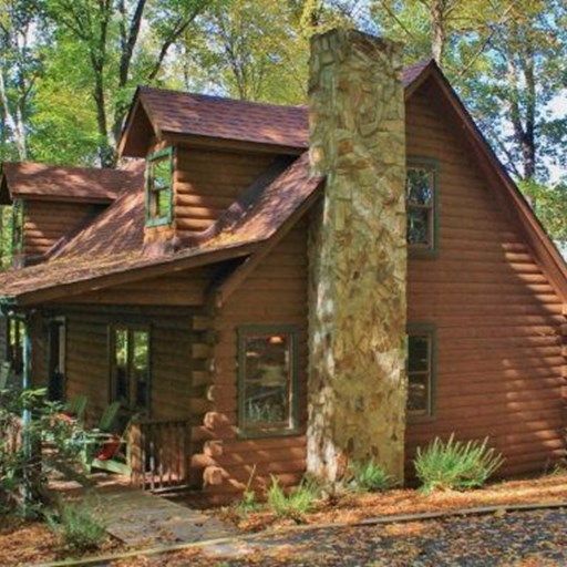 A log cabin with a stone chimney in the middle of the woods.