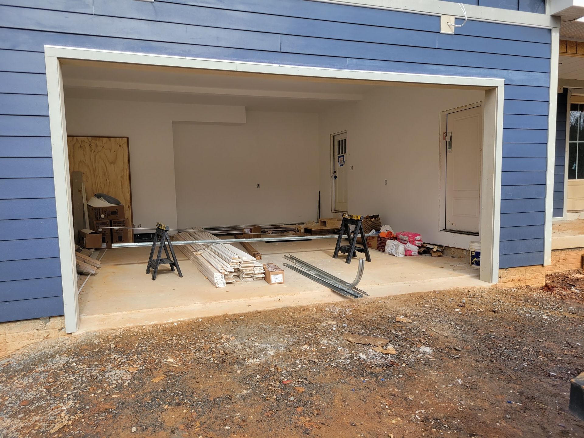 A garage with a blue siding and white trim is being built
