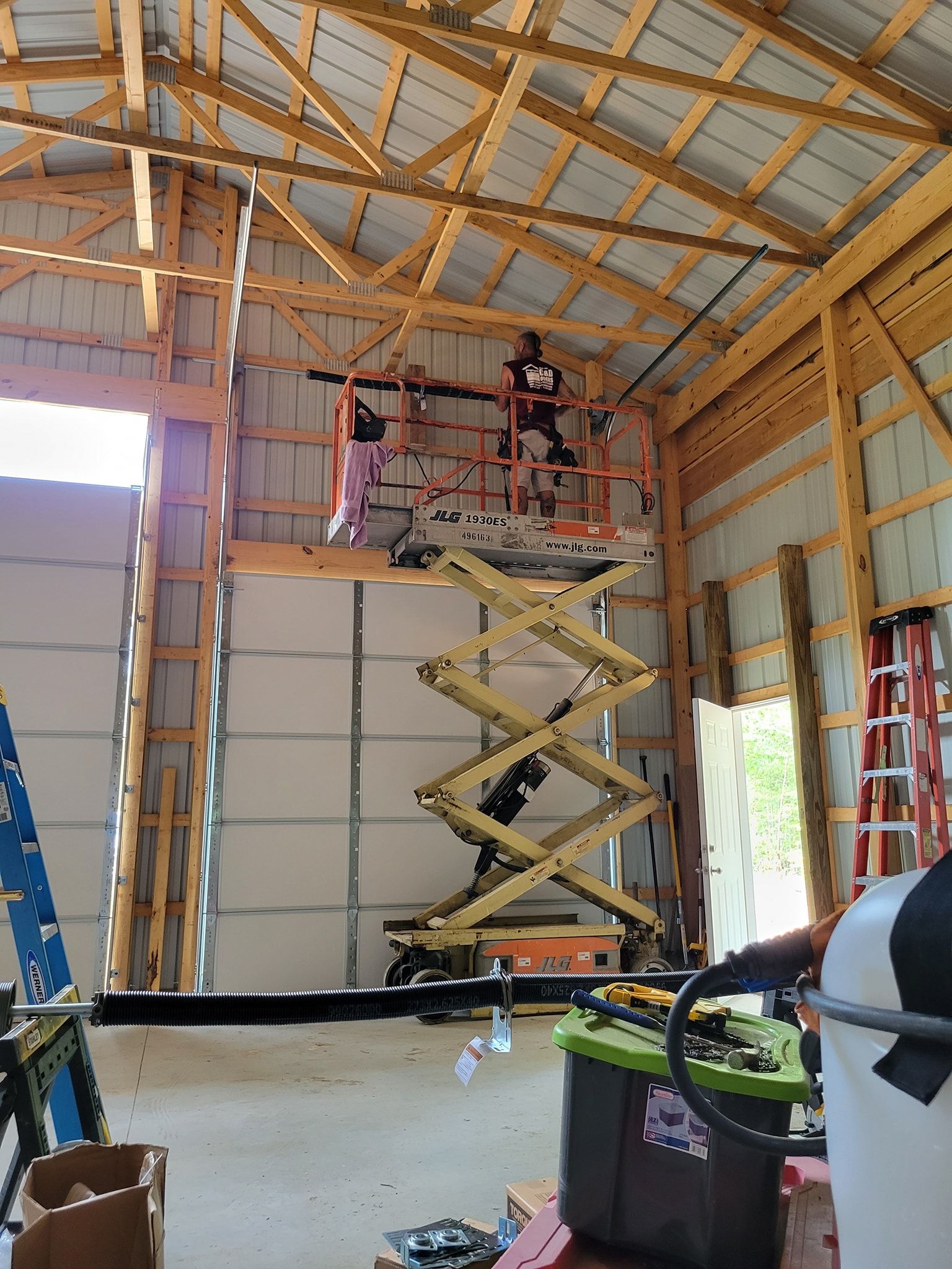 A man is standing on a scissor lift in a garage.