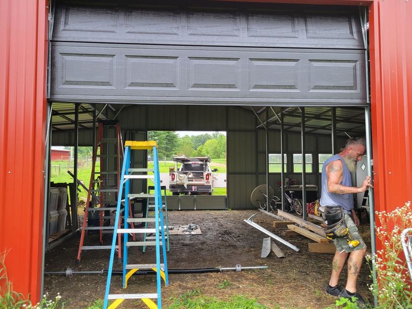 A man is working on a garage door with a ladder in the background.