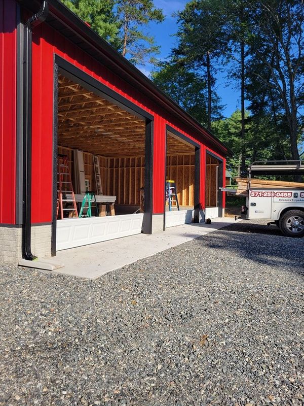 A white truck is parked in front of a red garage under construction.