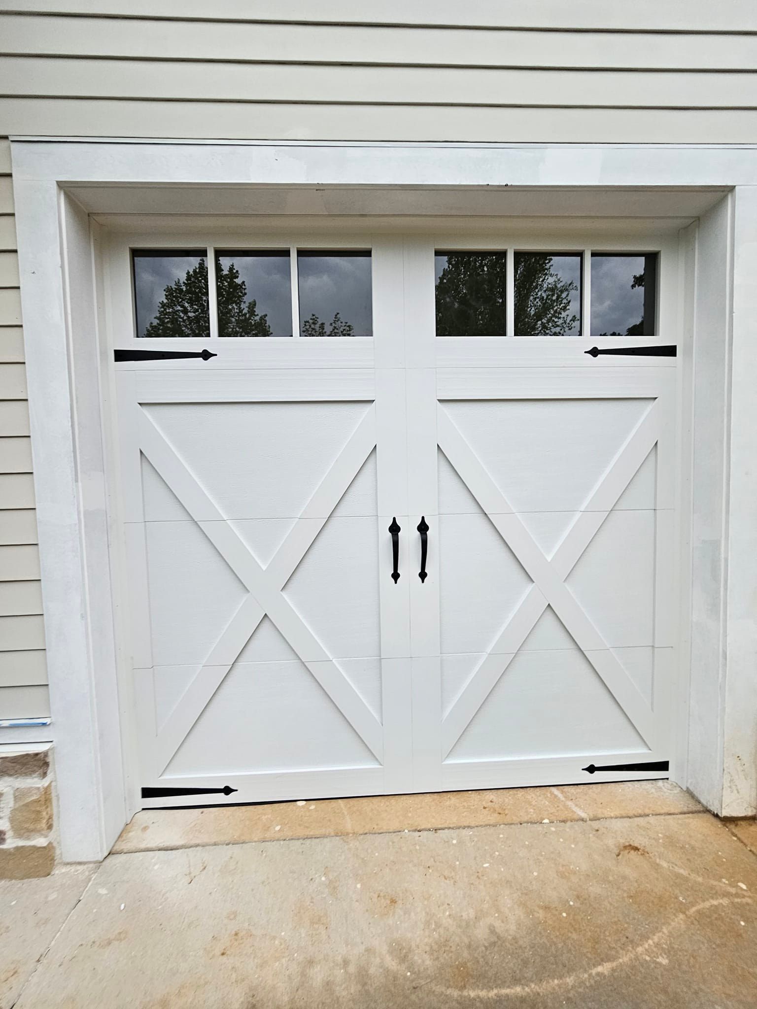 A white garage door with black handles and windows