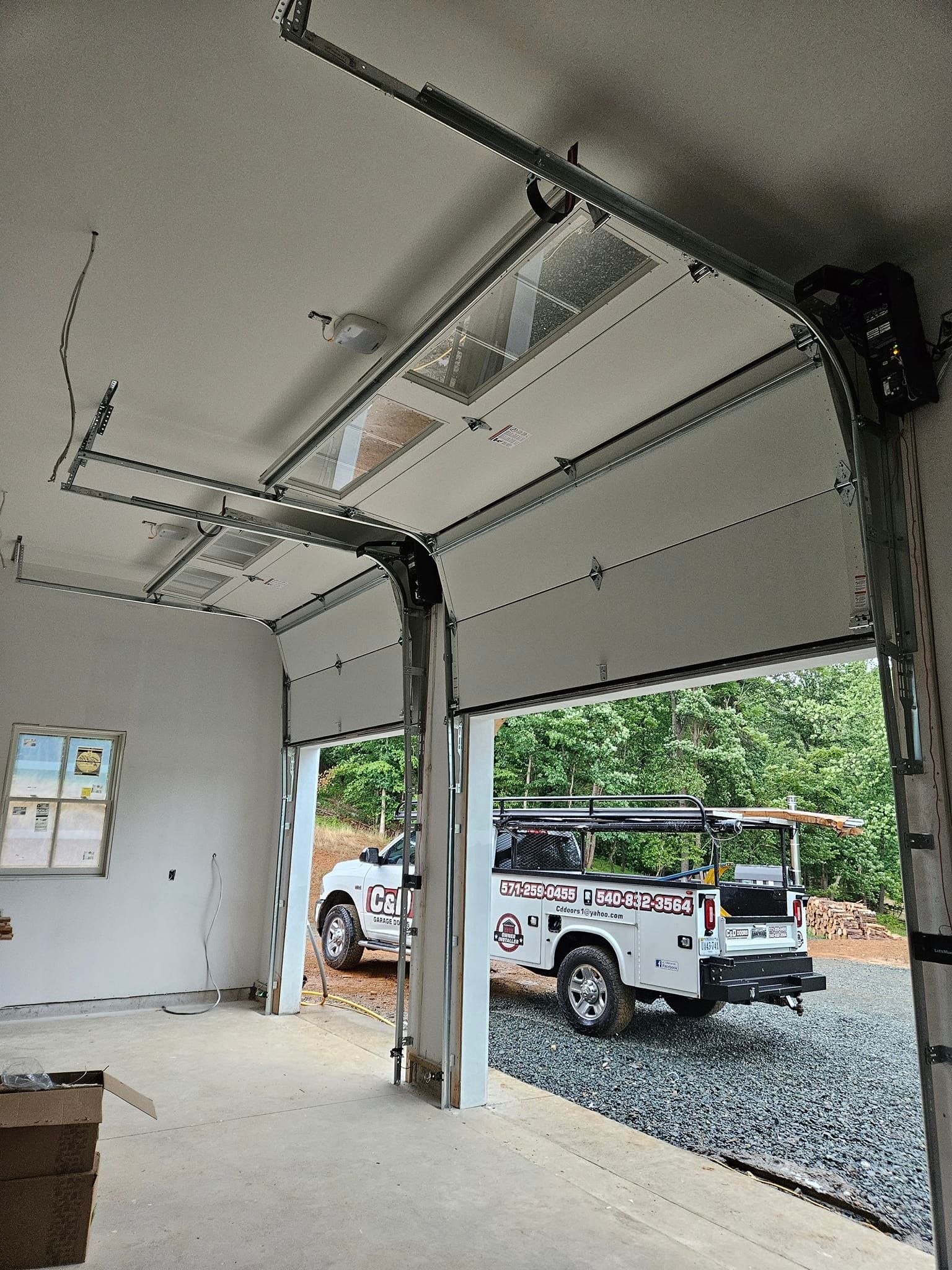 A white truck is parked in a garage with a garage door open.