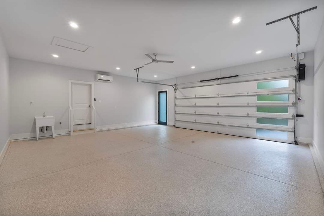 An empty garage with a white garage door and a ceiling fan.