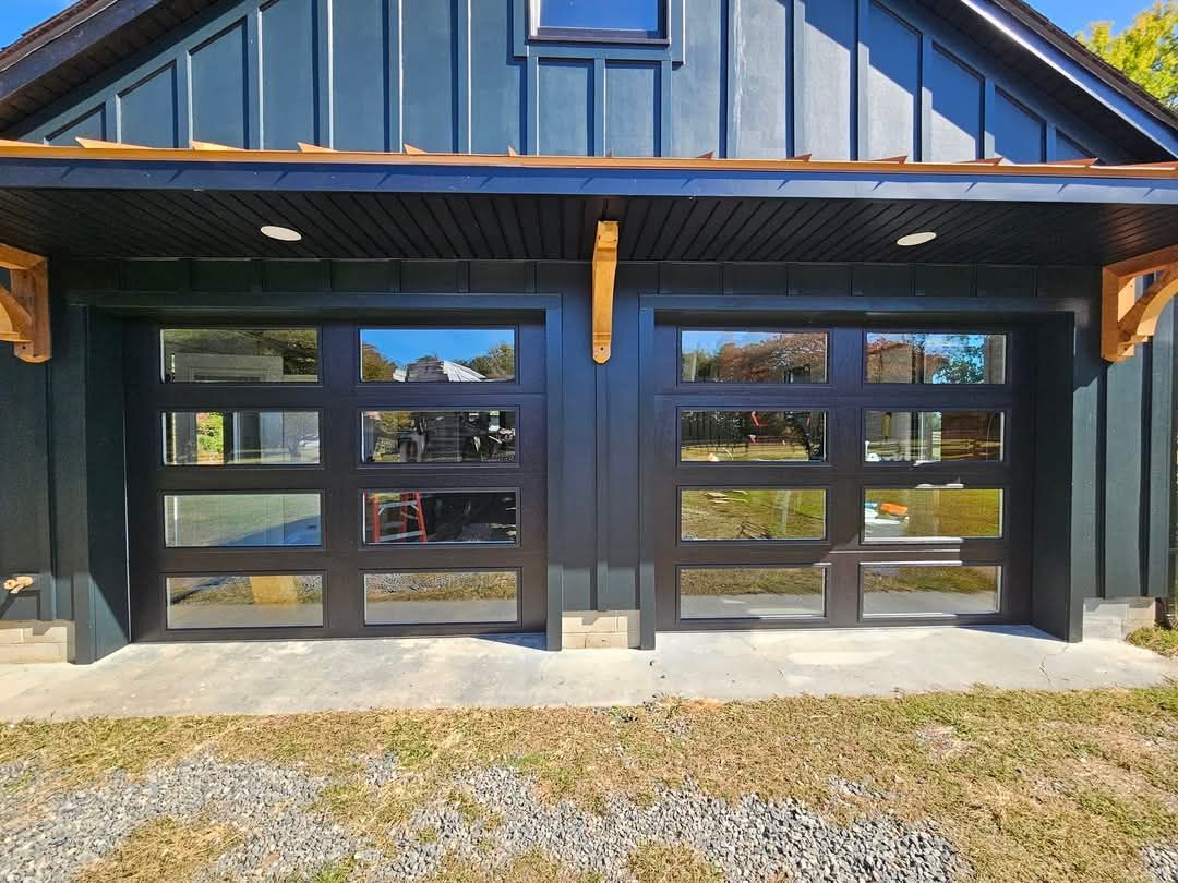 A black garage door with a lot of windows on a house.