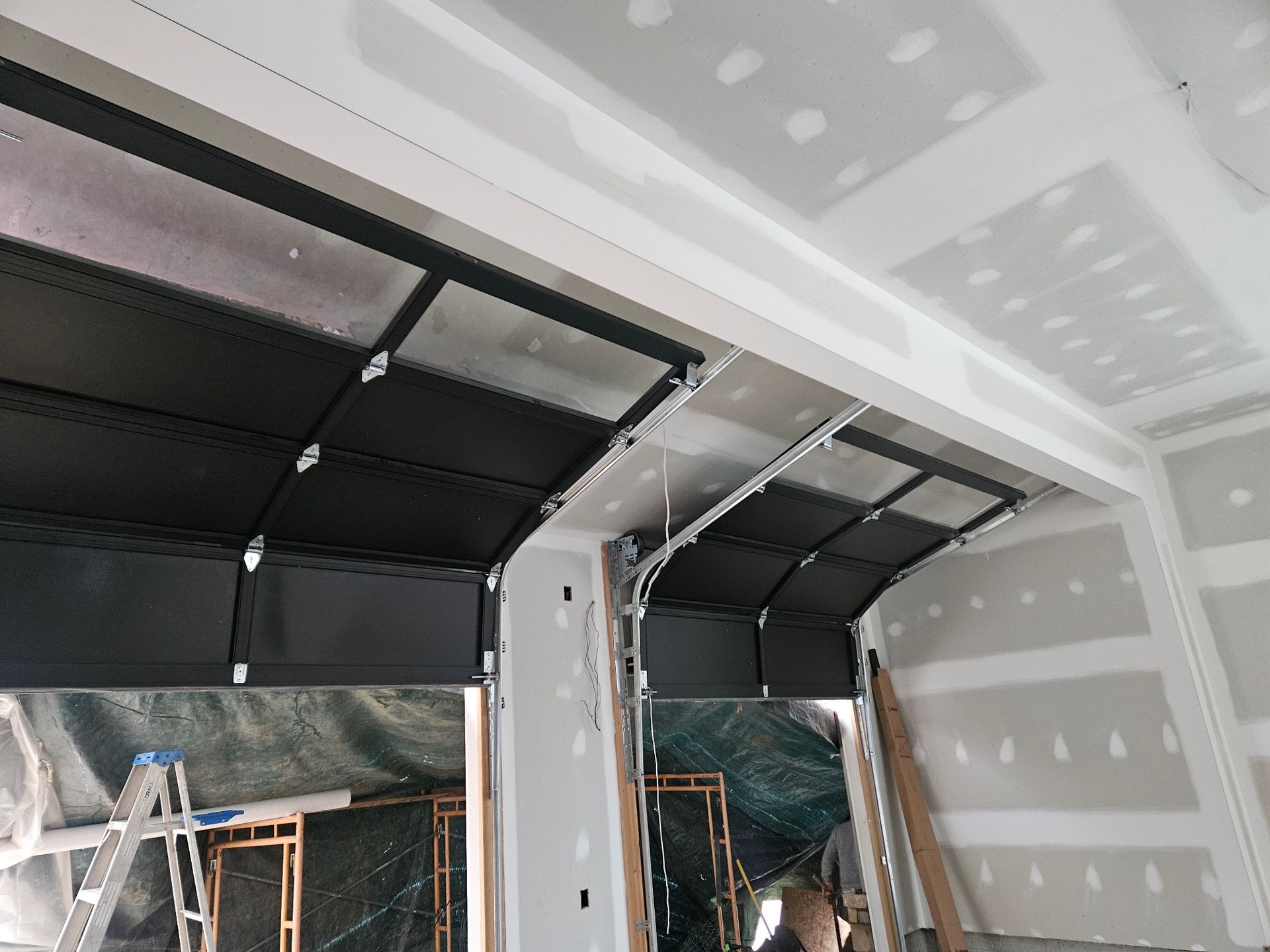 A garage door is open in a room with a ladder.