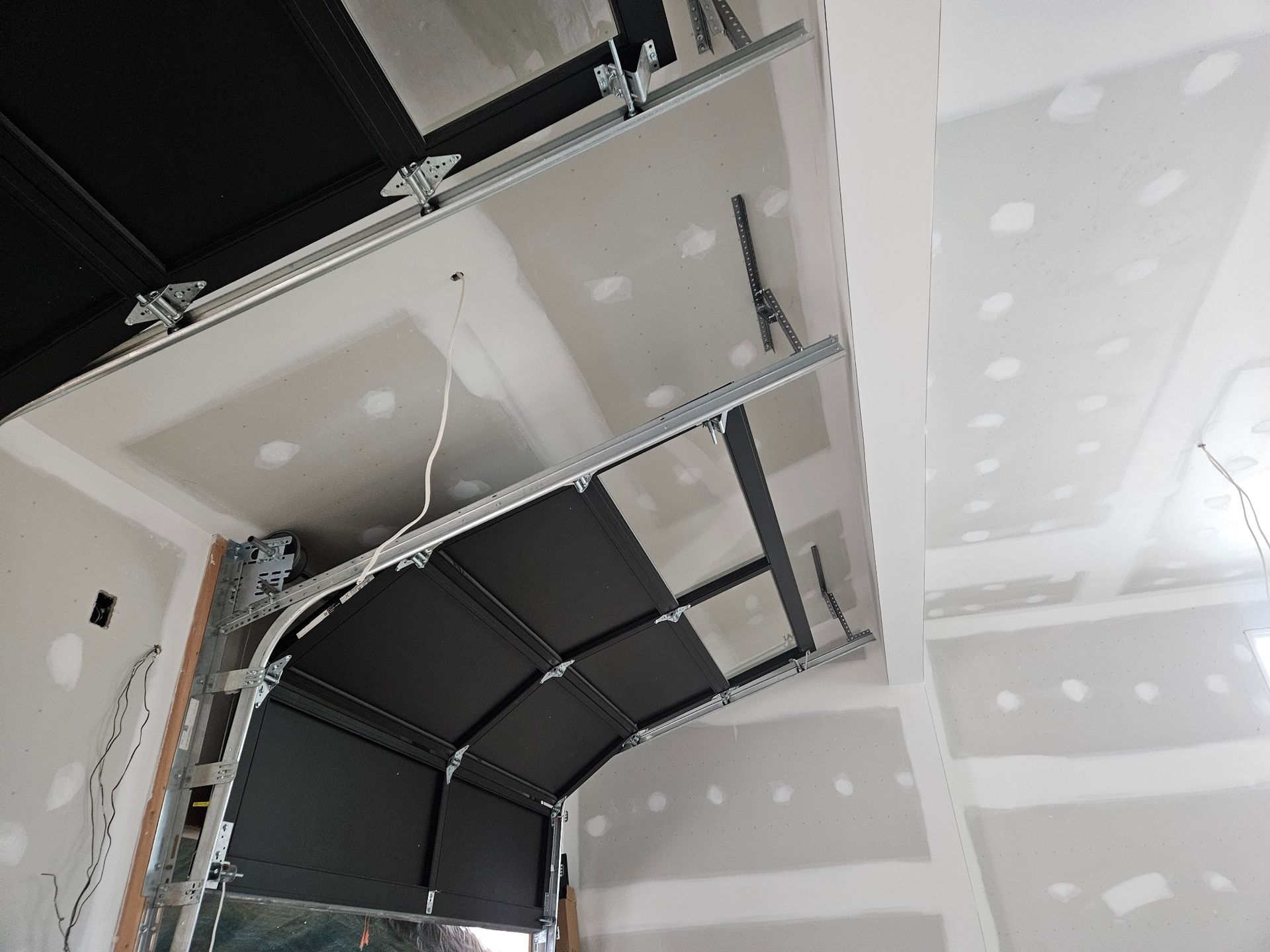 A garage door is open in a room with a white ceiling.