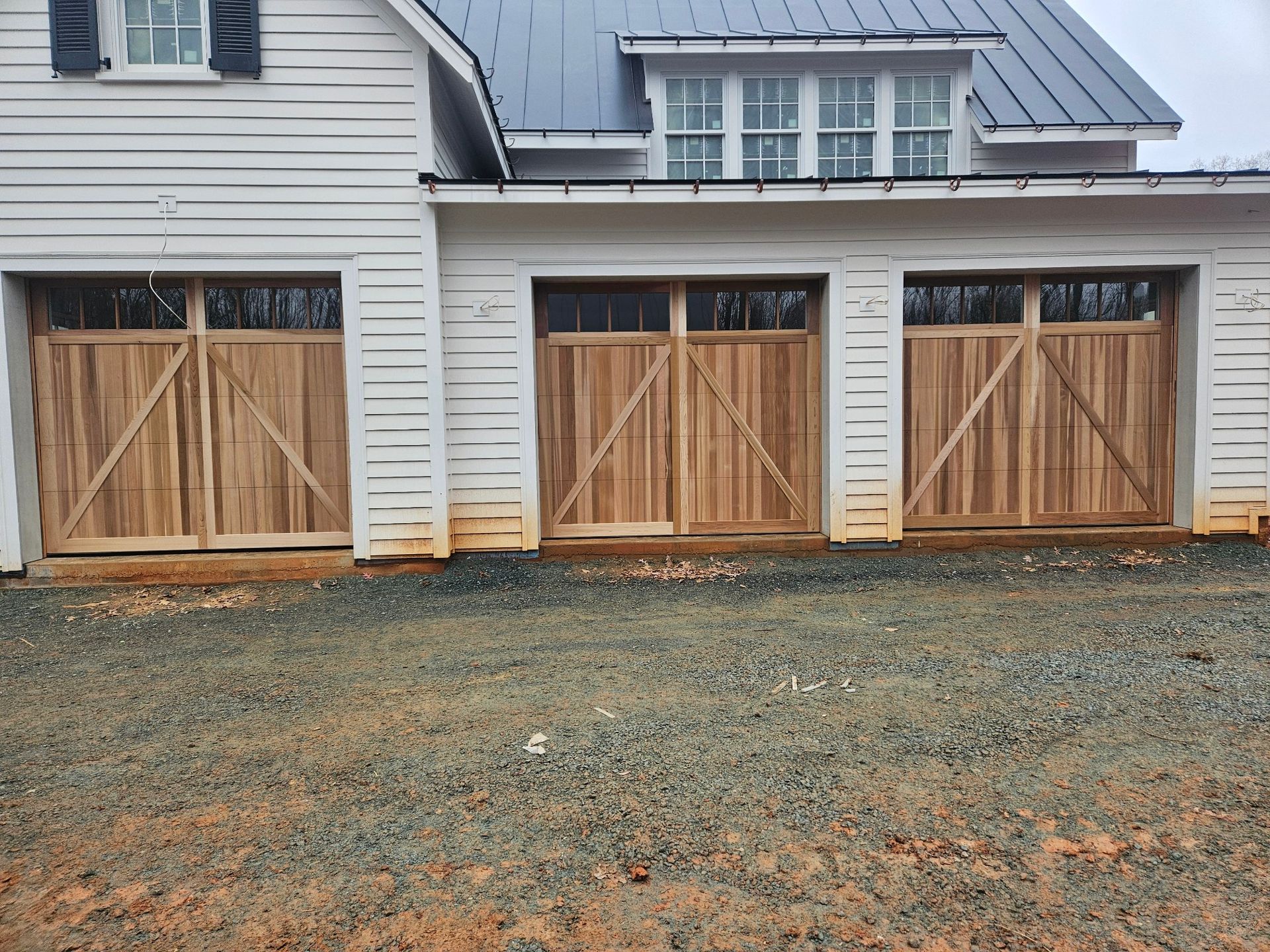 A white house with three wooden garage doors