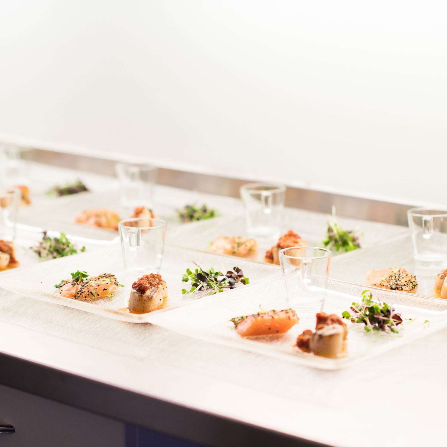 Forretter arrangert på gjennomsiktige brett med små glass, vist på en disk.