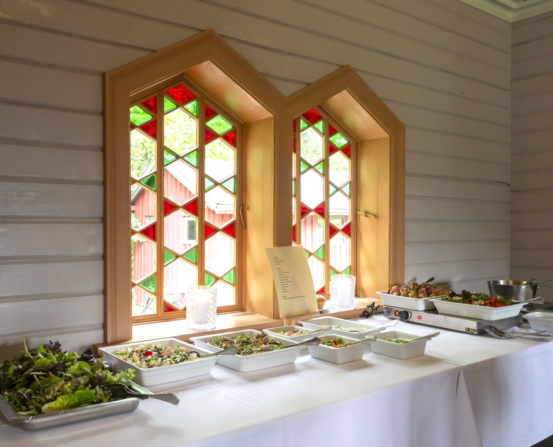 Vinduer med farget glass og sommerbuffet på Sæterhytten selskapslokale
