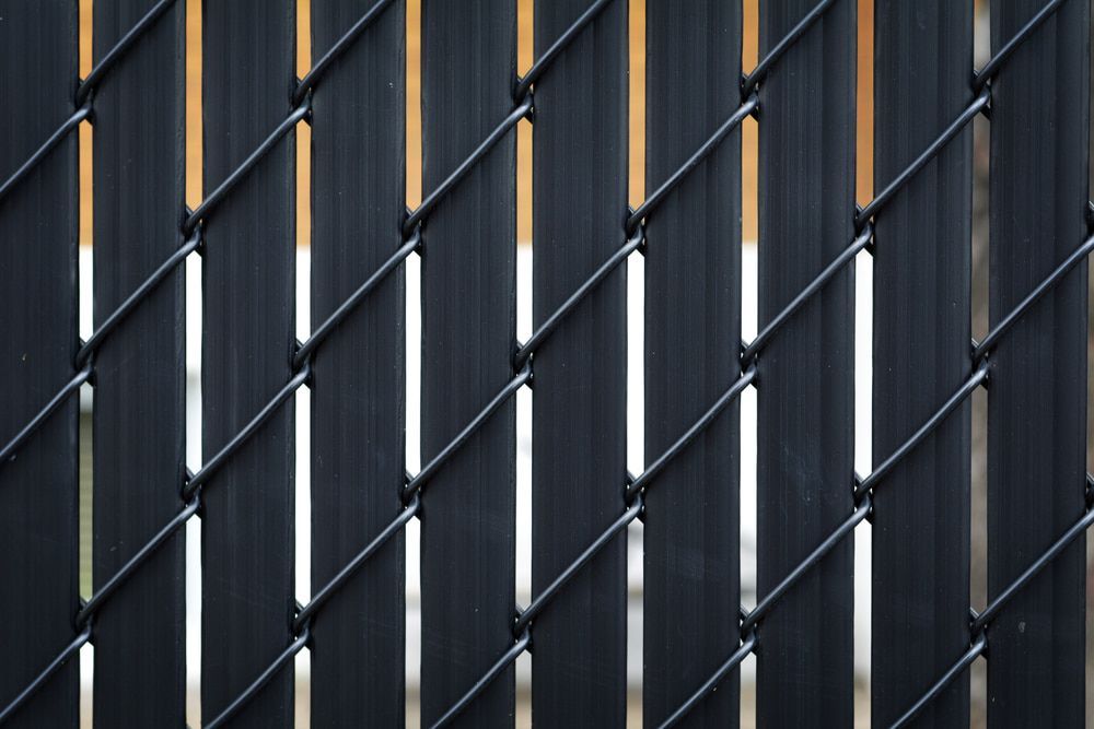 Black Chain-link Fence With Vertical Dark Plastic Slats, Creating a Pattern — Trade Fencing Supplies in Moolap, VIC