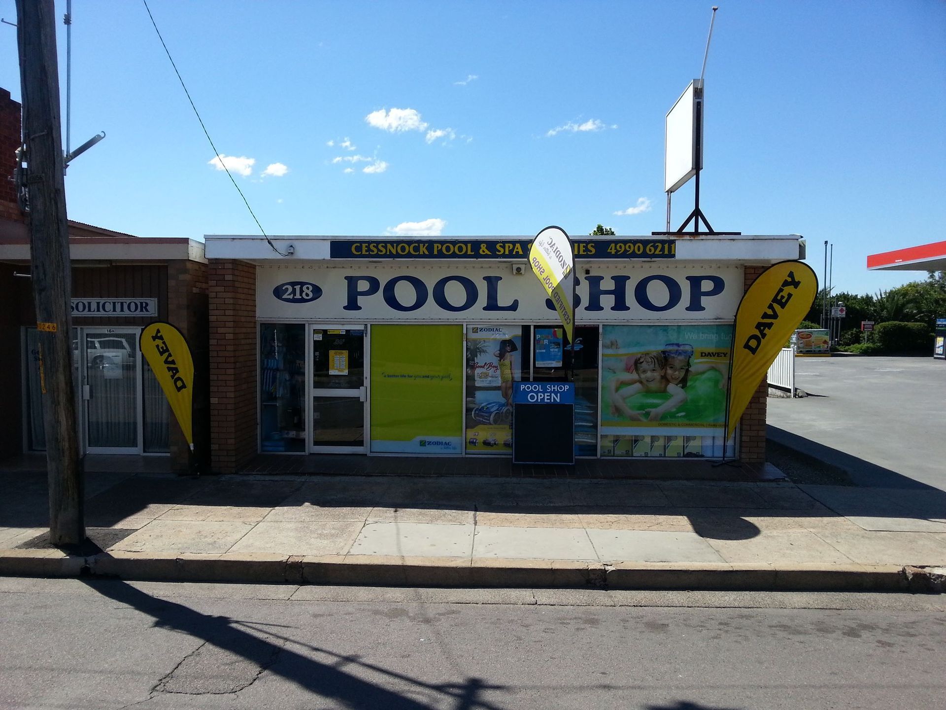A Man is Cleaning a Swimming Pool With a Vacuum Cleaner — Cessnock Pool Shop in Cessnock, NSW
