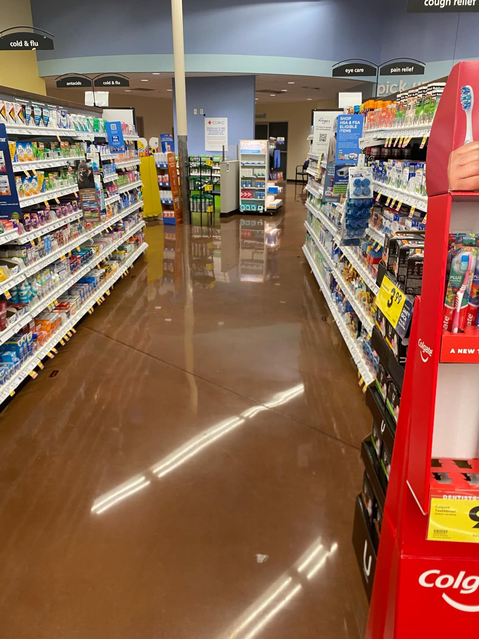 Grocery store aisle with shelves of products and shiny, reflective floor.