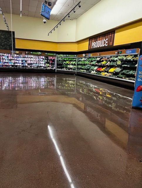Empty grocery store produce section with shiny brown floor, bright lighting, and colorful displays.