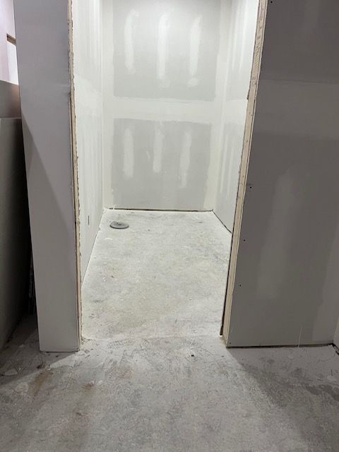 Framed doorway leads to a small room with unfinished walls and concrete floor, likely under construction.