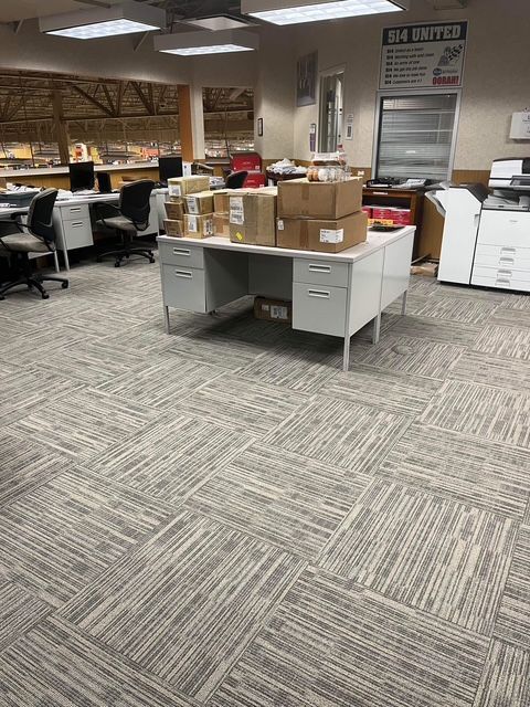 Office interior with white desk, boxes, and gray patterned carpet.