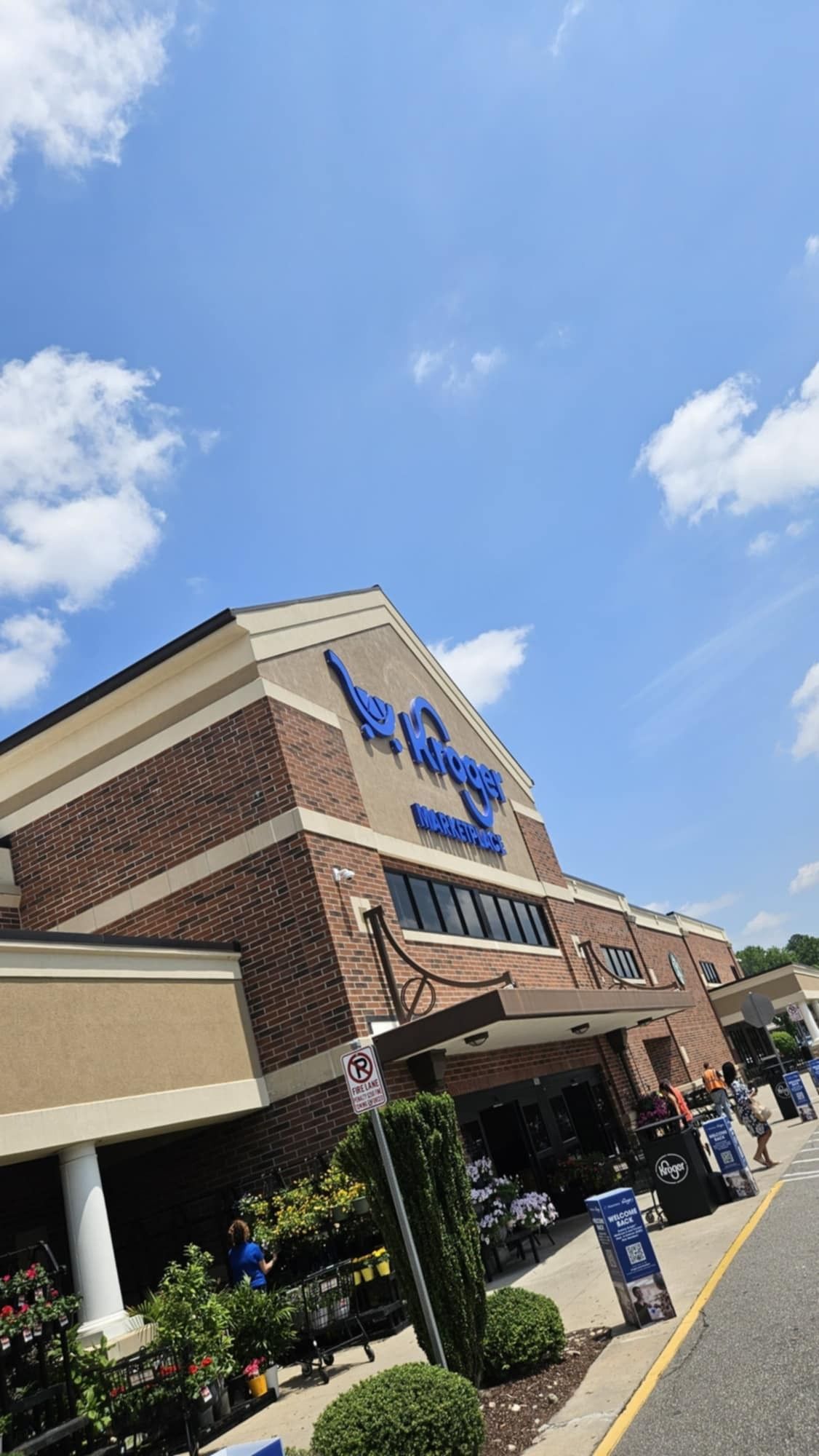 Exterior of a Wegmans grocery store on a sunny day with blue sky and clouds.