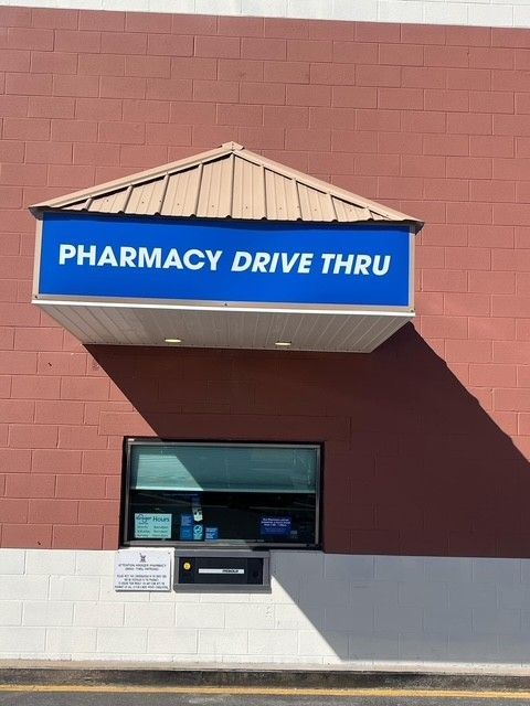 Pharmacy drive-thru window with a blue sign above. The building is brick.