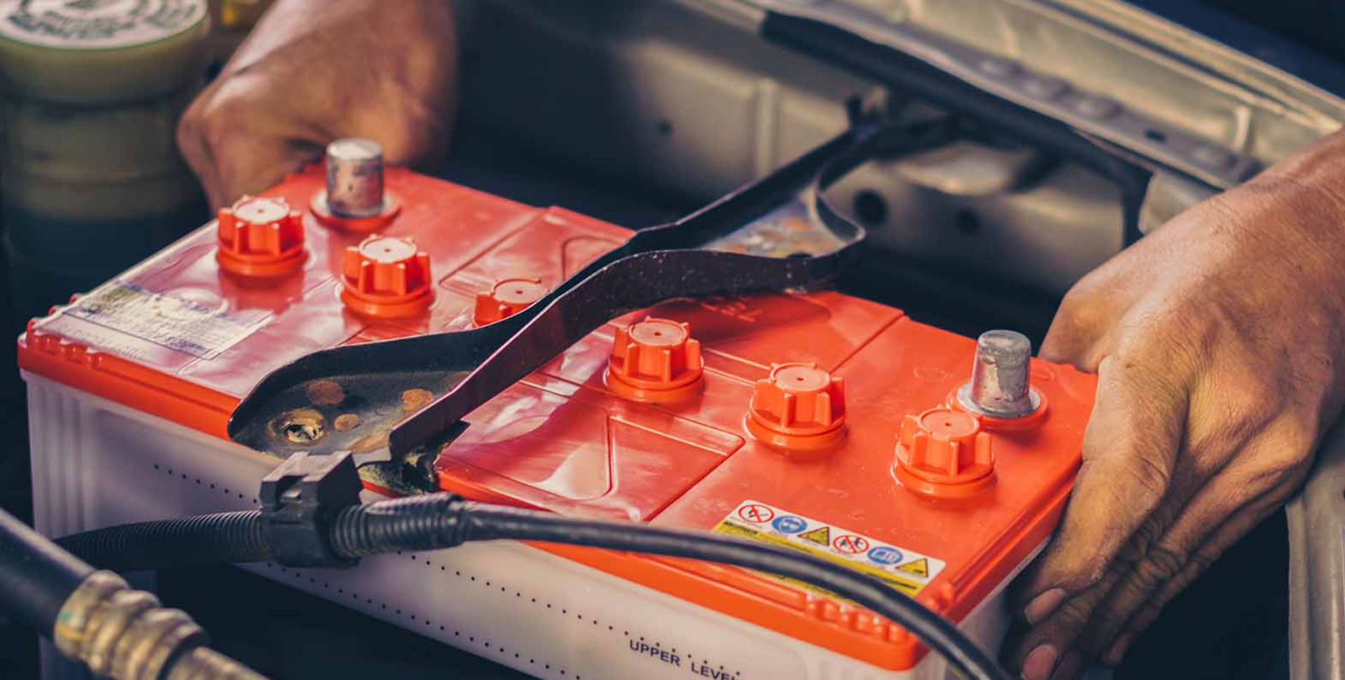 A roadside car mechanic installing a car battery for a customer during a mobile auto car battery replacement service call.