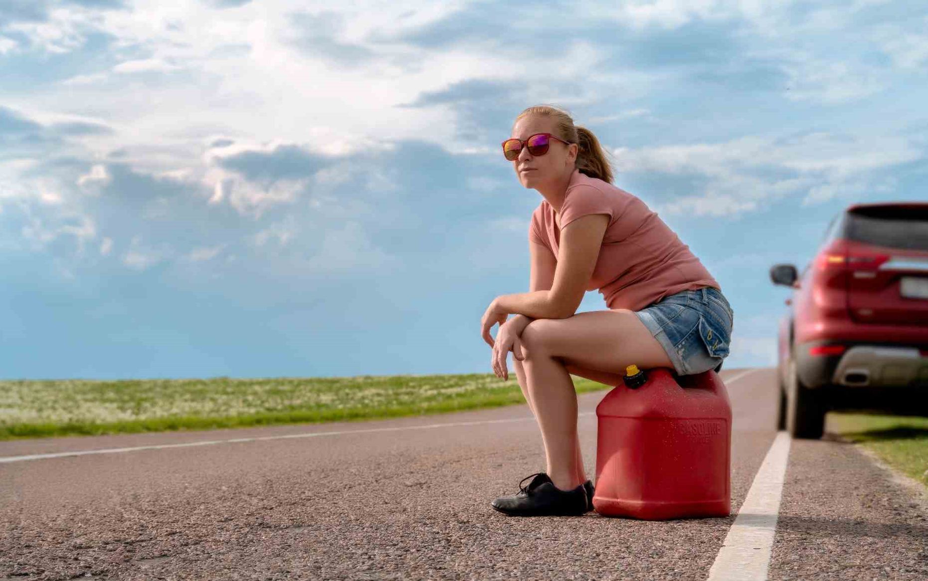 A woman sitting on an empty fuel tank waiting for fuel delivery or gas delivery