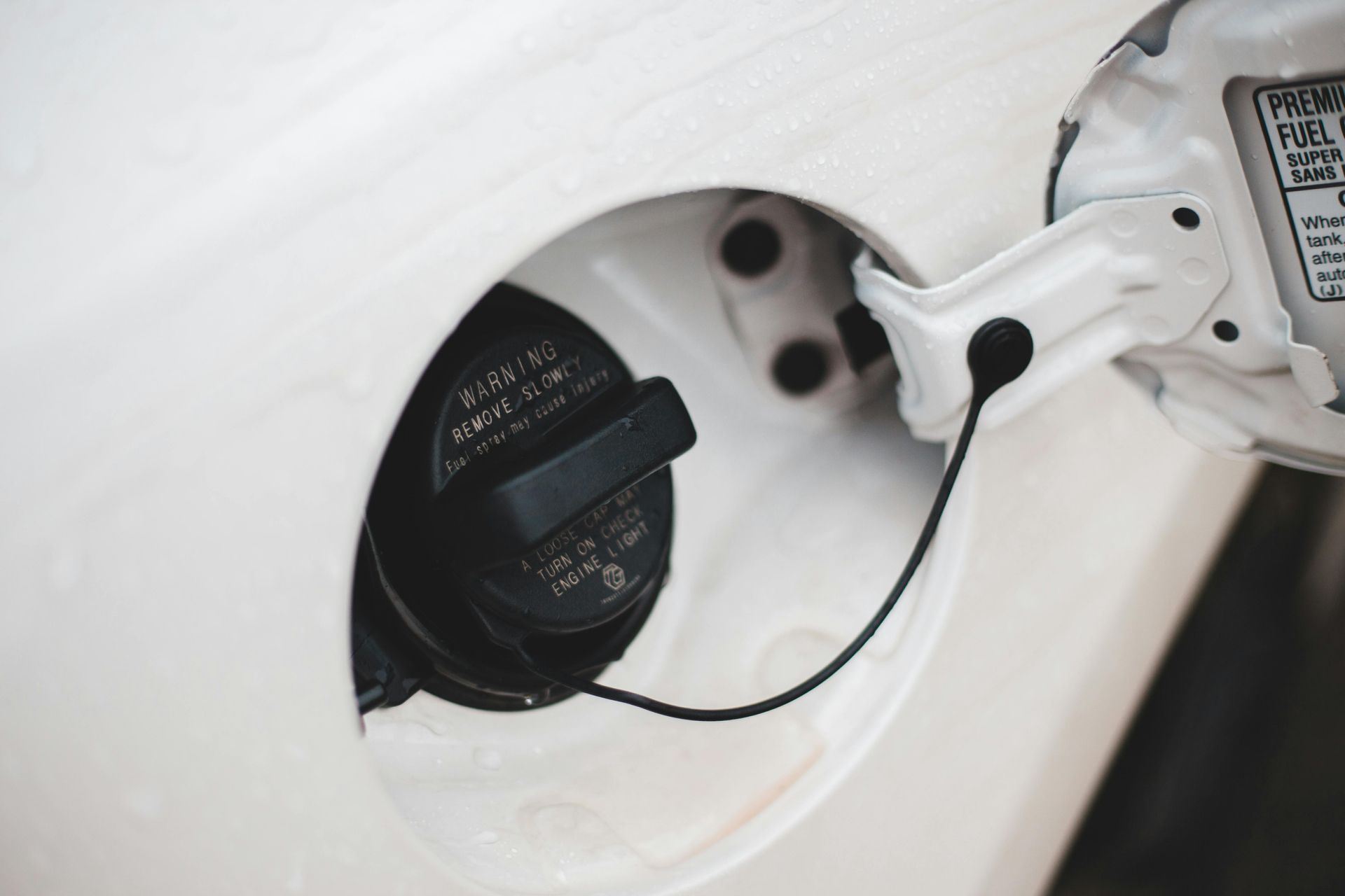 A vehicle's gas cap is being opened by a technician who is about to deliver fuel to the vehicle.