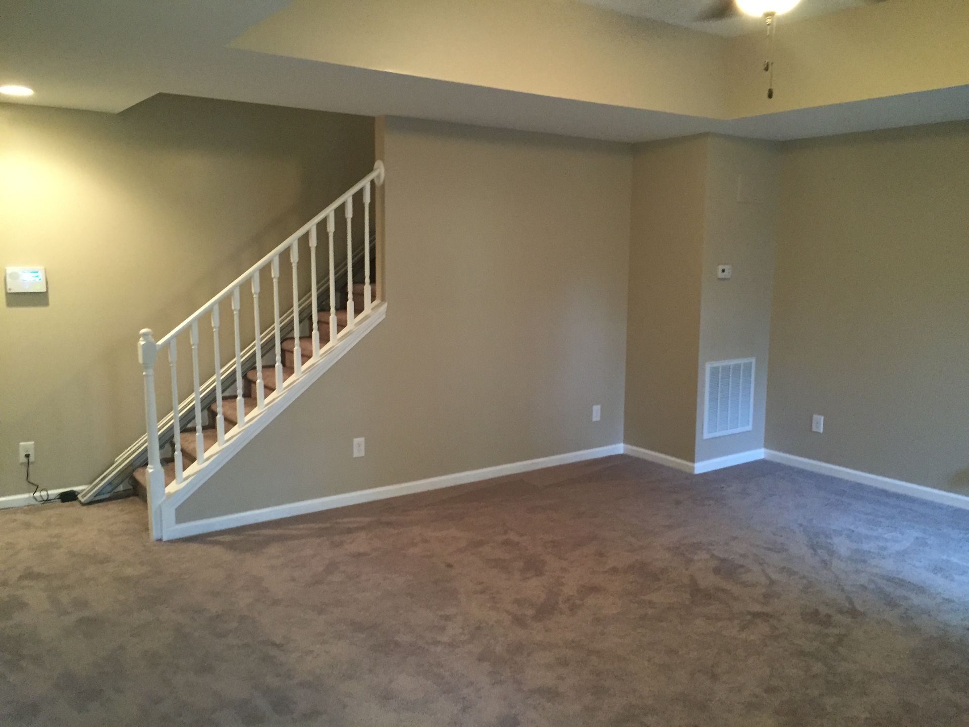 Finished drywall and paint project after removing damaged drywall and fixing a damaged staircase highlighted by a simple white hand rail, fresh carpet and a gentle green paint color in Miramar Beach, Florida