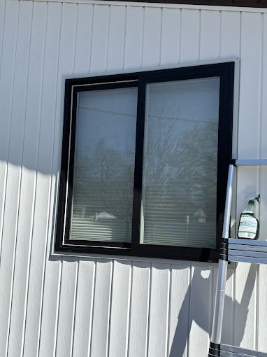 A window on the side of a white building with a black frame.