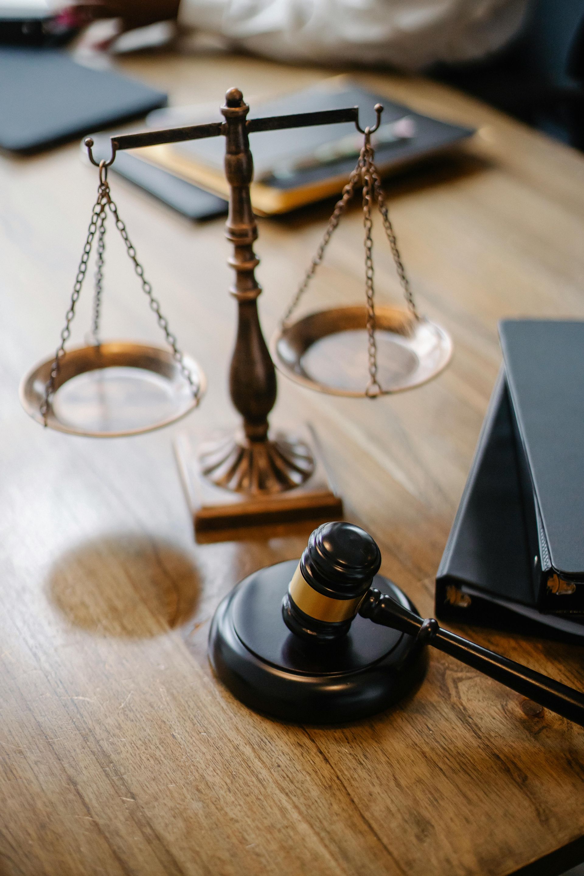 Judge’s gavel beside scales of justice on a wooden desk with books and papers
