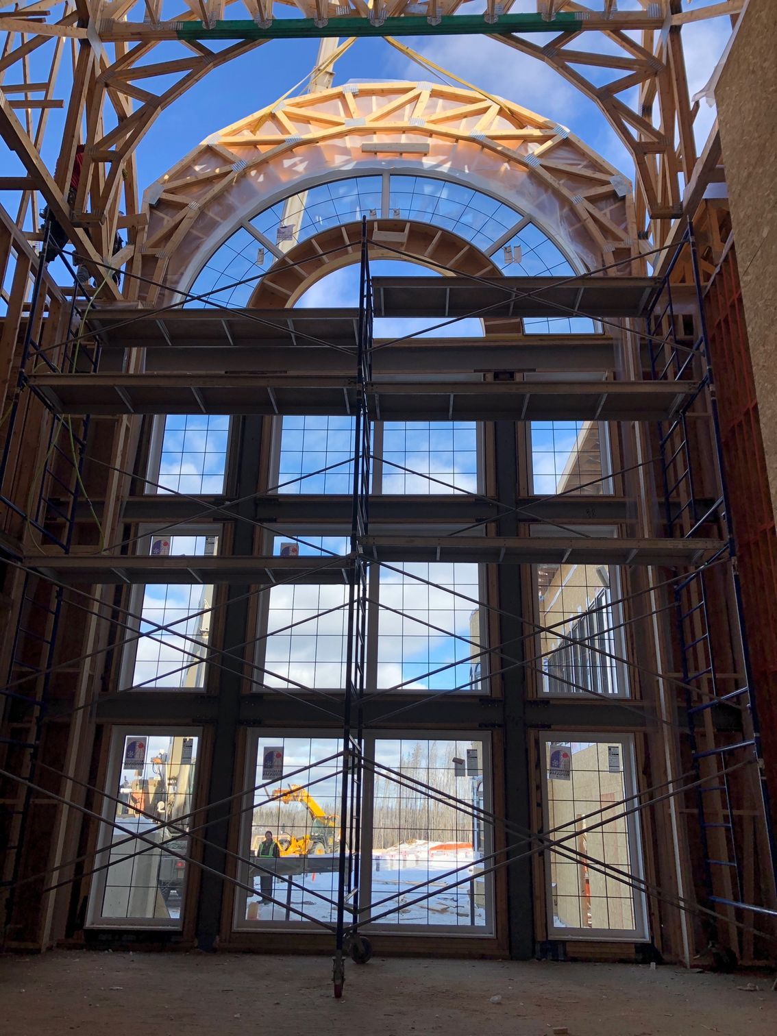 A large window in a building under construction with scaffolding around it.