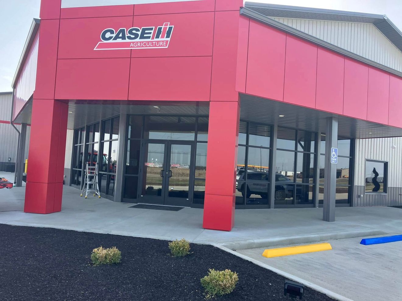 Case IH agricultural equipment dealership building with bright red panels, glass storefront, and paved parking.