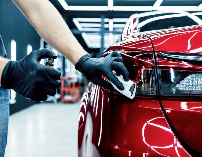 A person is polishing a red car in a garage.