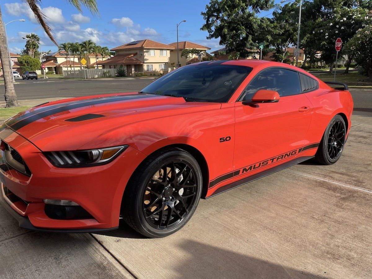 A red ford mustang is parked in a parking lot.
