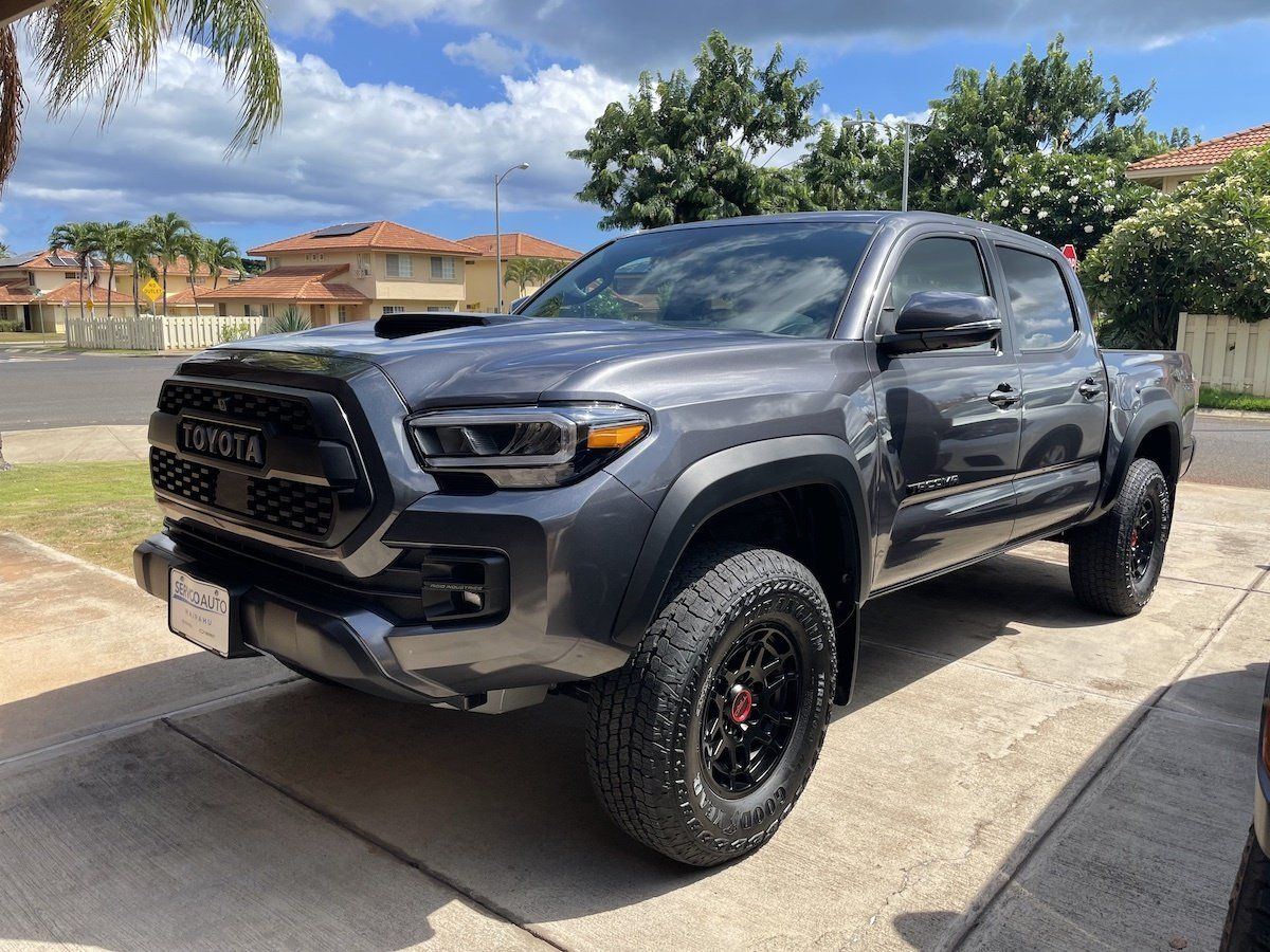 A black toyota tacoma truck is parked in a driveway.