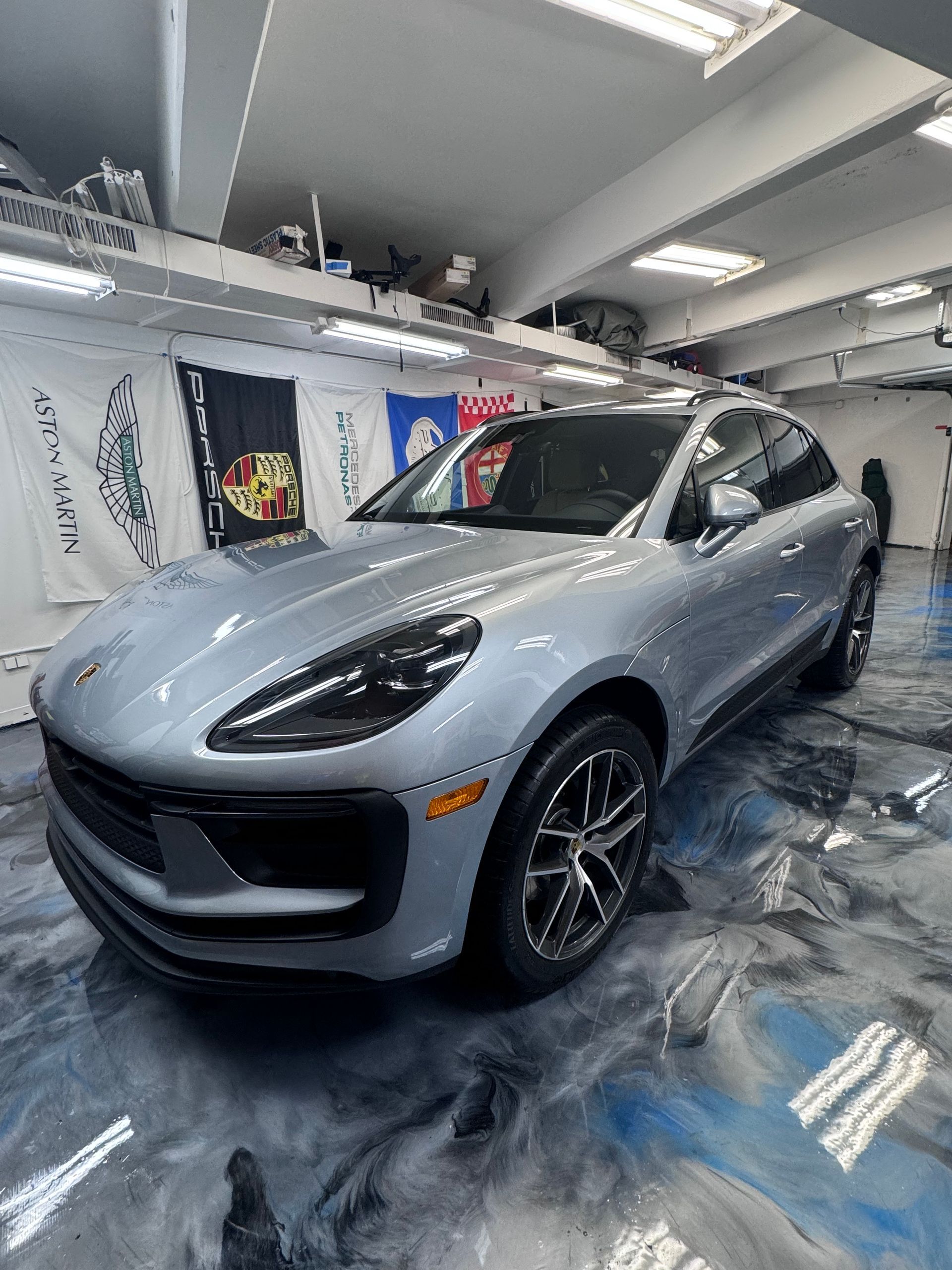 A silver porsche macan turbo is parked in a garage.
