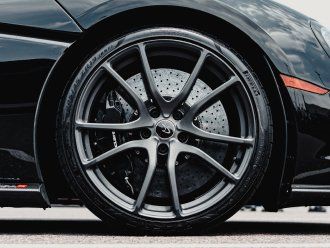 A close up of the front wheel of a black sports car.
