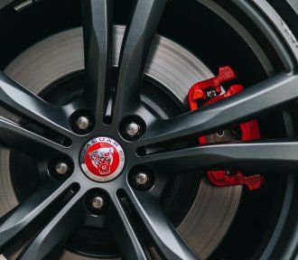 A close up of a jaguar wheel with red brake calipers