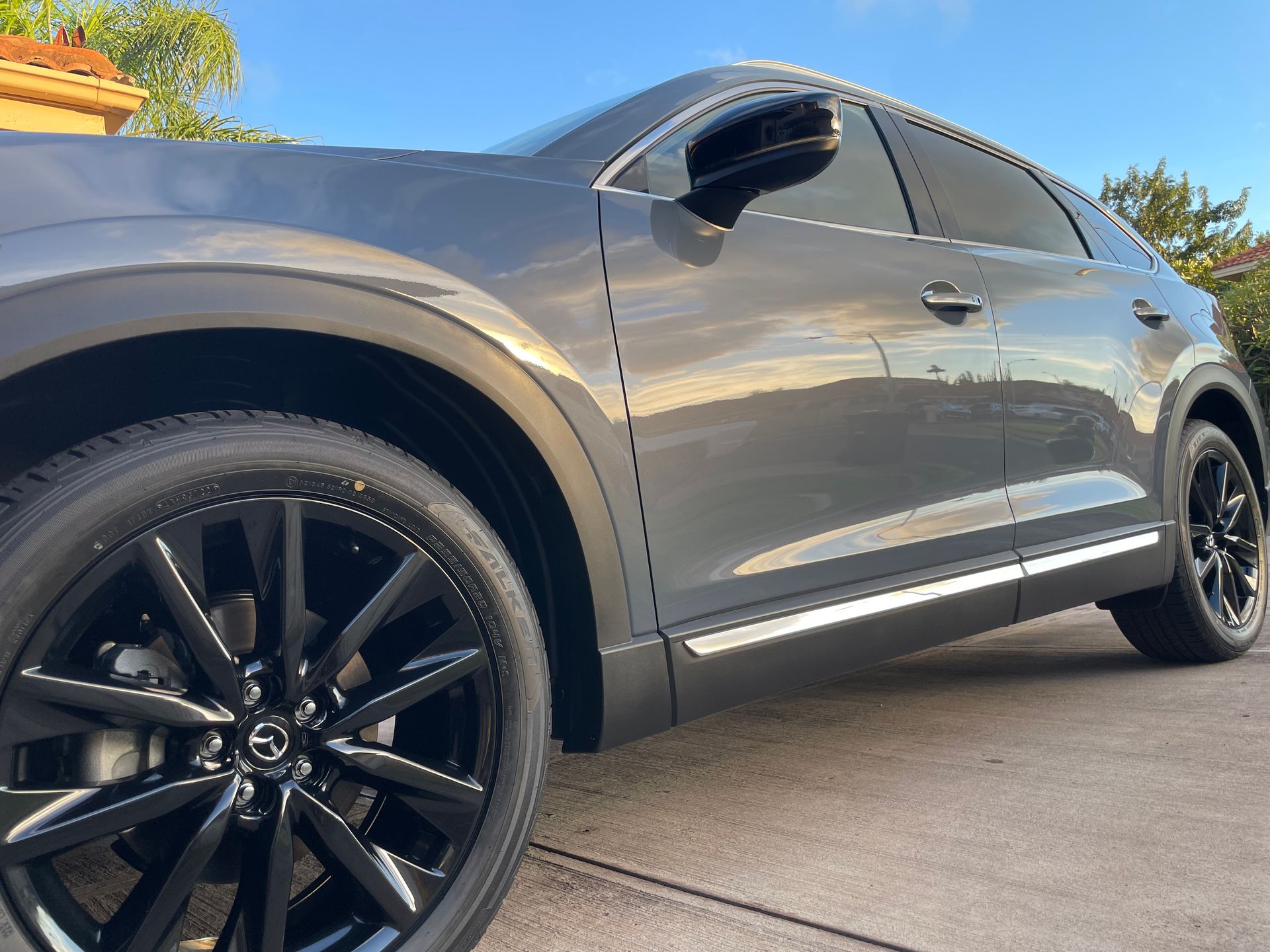 A gray car with black wheels is parked in a driveway.