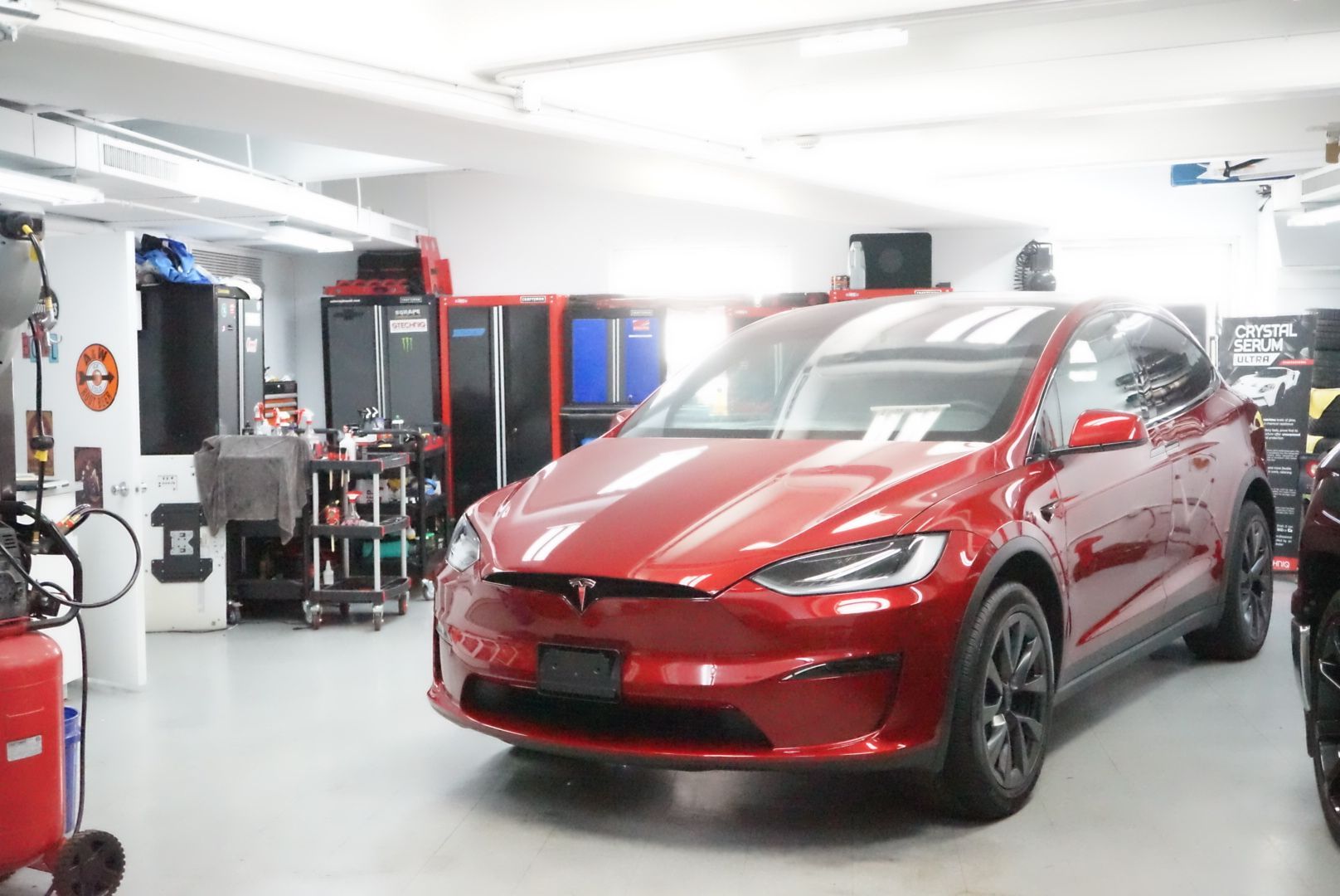 A red tesla model x is parked in a garage.