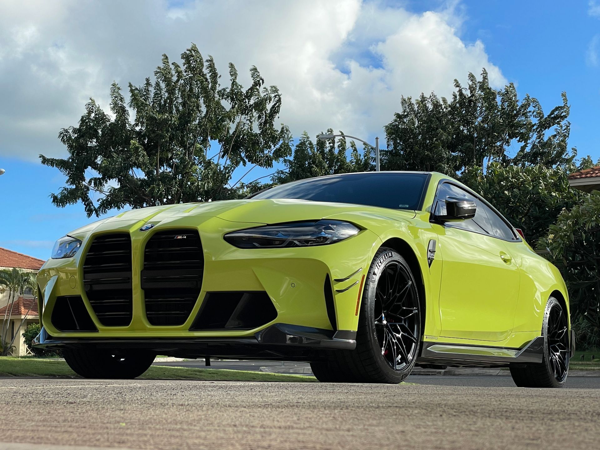 A yellow bmw m4 is parked on the side of the road.