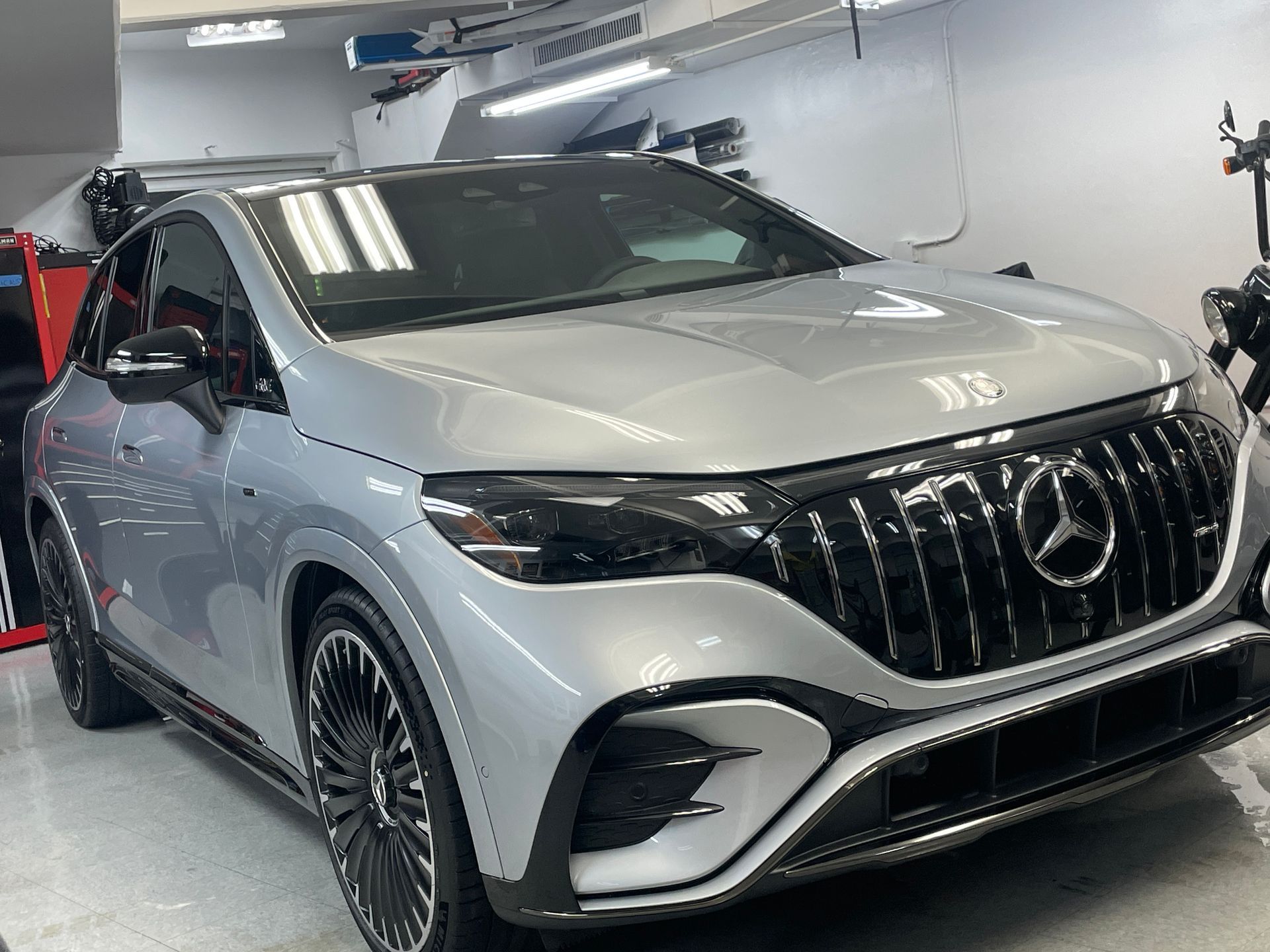 A silver mercedes benz eqs is parked in a garage.